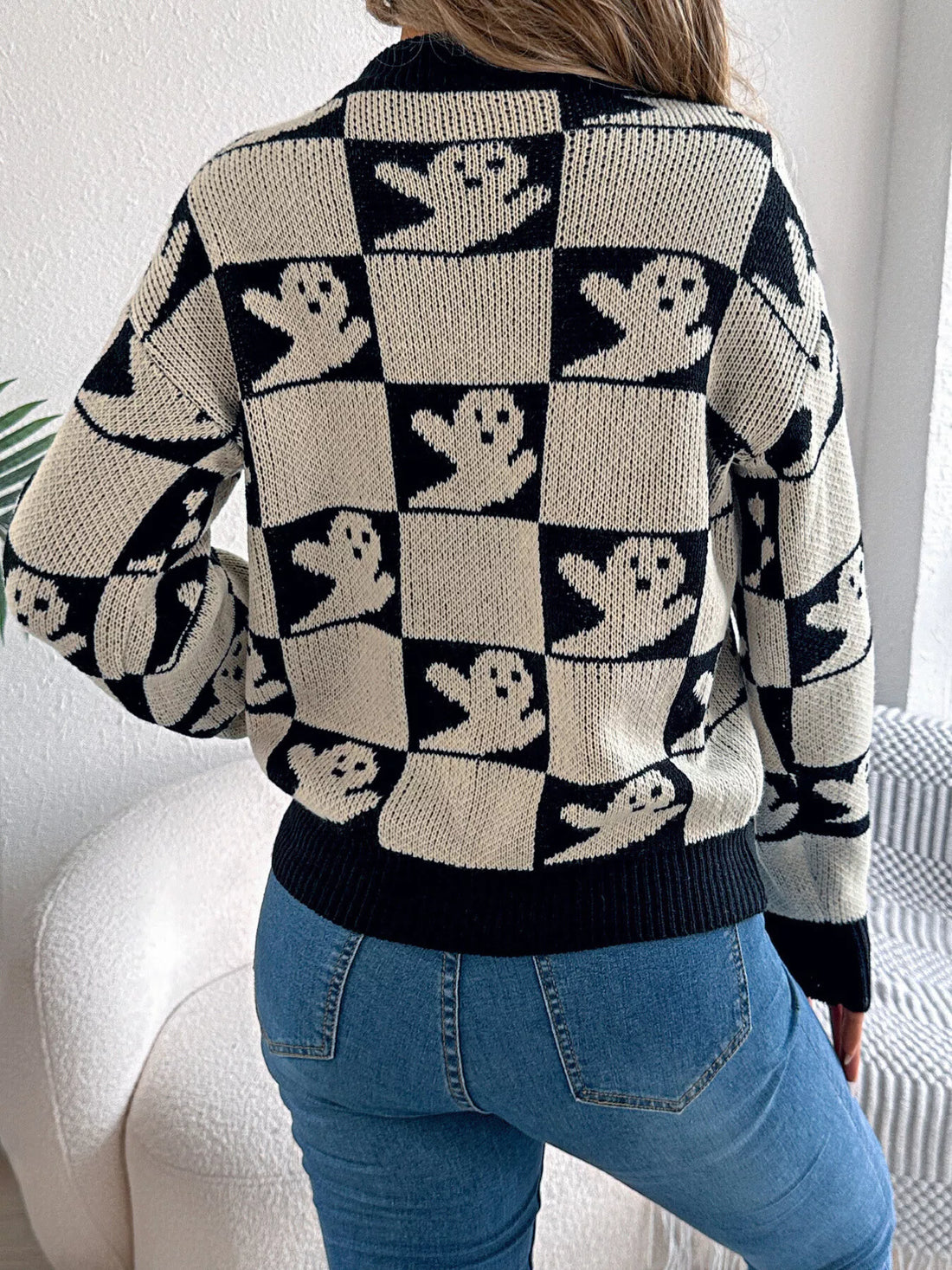 Back view: black and cream checkerboard Halloween sweater with ghost face pattern