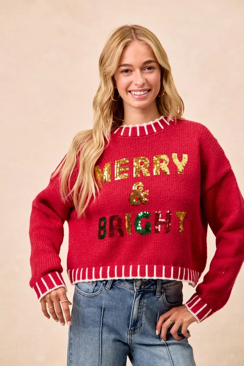 Red crewneck knit sweater with sequin “Merry & Bright” text and striped rib edges