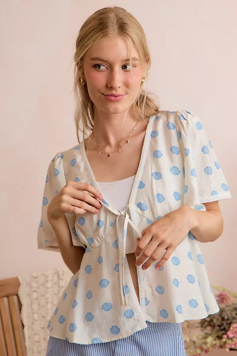 Ivory dot-print tie-front blouse with flutter sleeves and V-neck front tie.