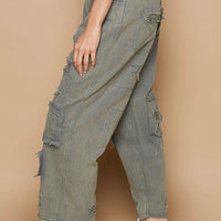 Distressed wide-leg denim pants with raw hem, layered cargo pockets