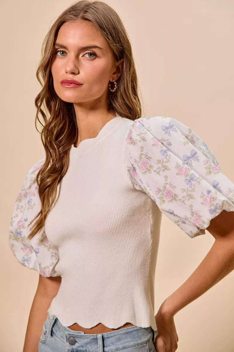White knit top with puff floral sleeves and scalloped hem; crew neckline