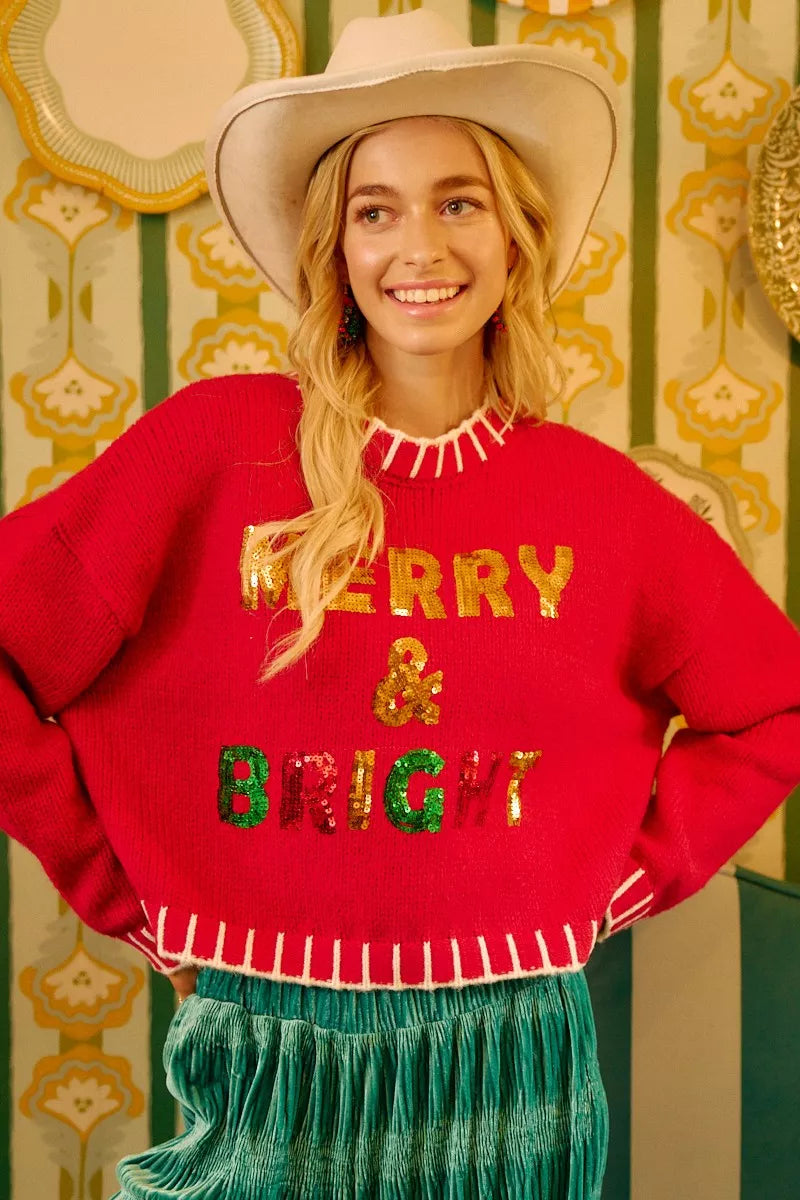 Red sequin Christmas sweater with “MERRY & BRIGHT” lettering and white fringe edge