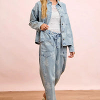 Light blue denim jacket with white floral print and front pockets, worn with matching pants