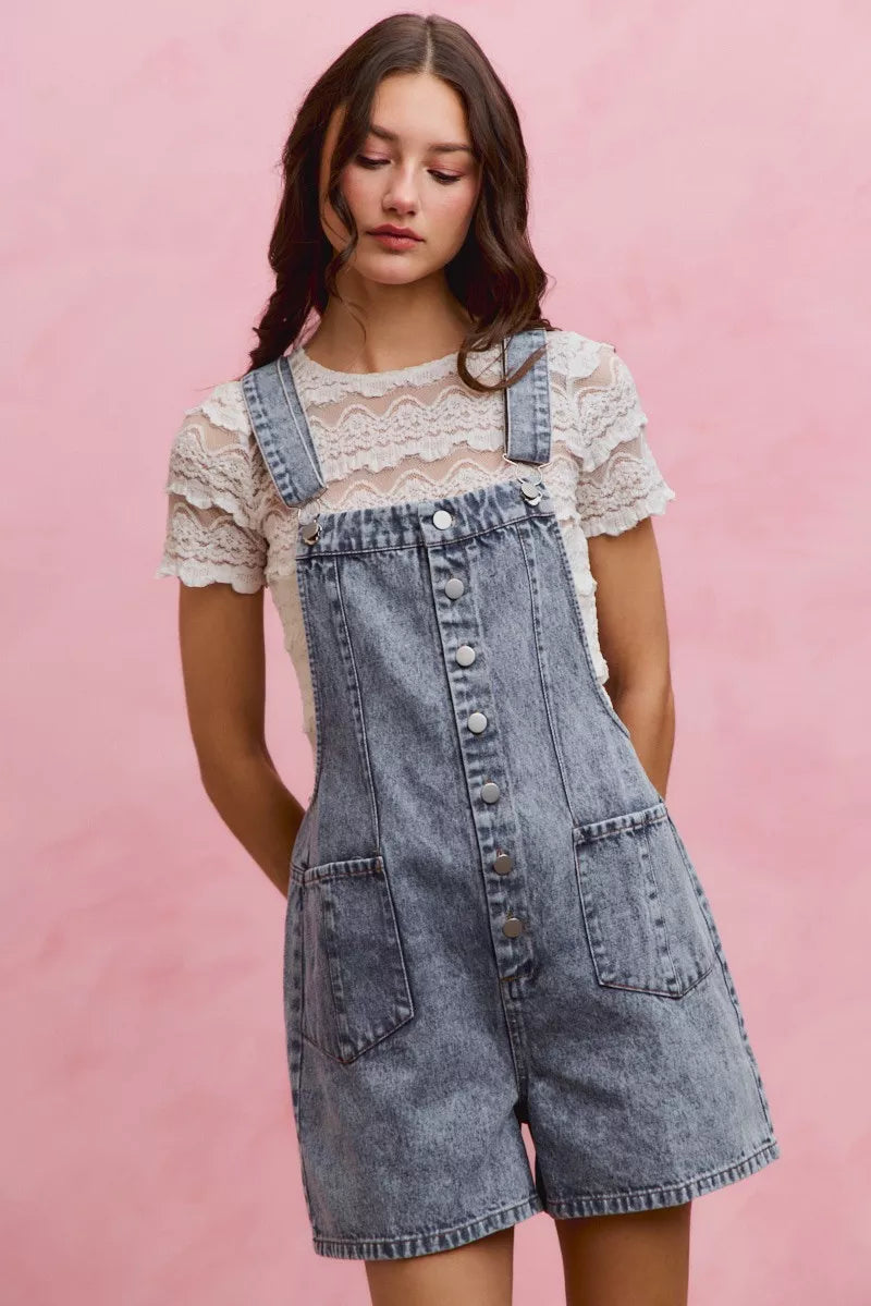 Light wash denim overall romper with adjustable straps and front buttons, chest pocket
