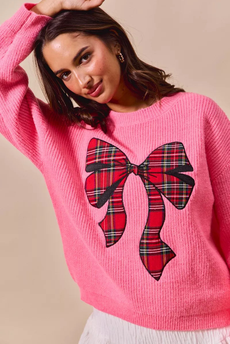 Pink crewneck sweater with plaid ribbon bow detail centered on front