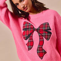 Pink crewneck sweater with plaid ribbon bow detail centered on front