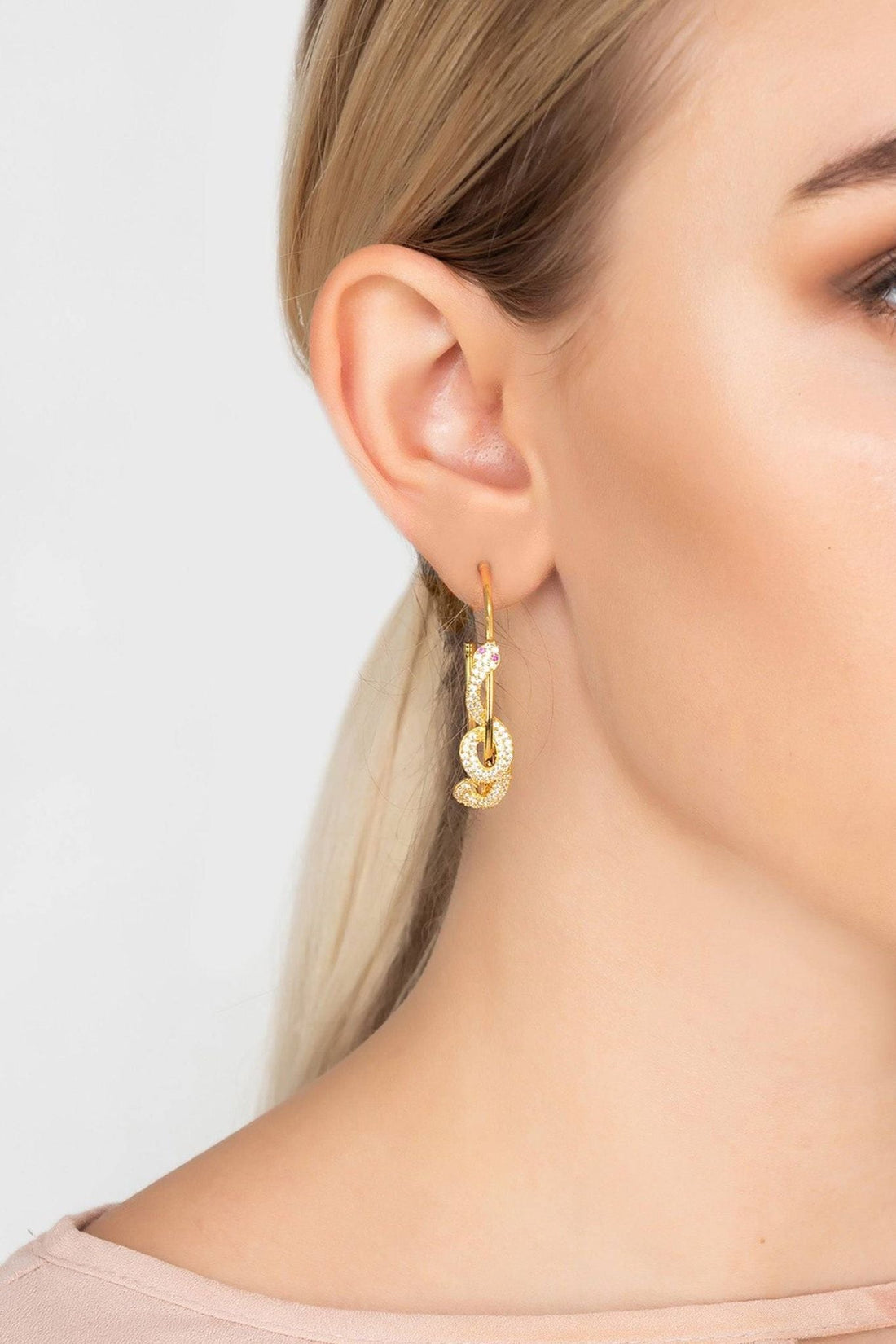 Gold serpent hoop earring with sparkling stones, shown on an ear close-up