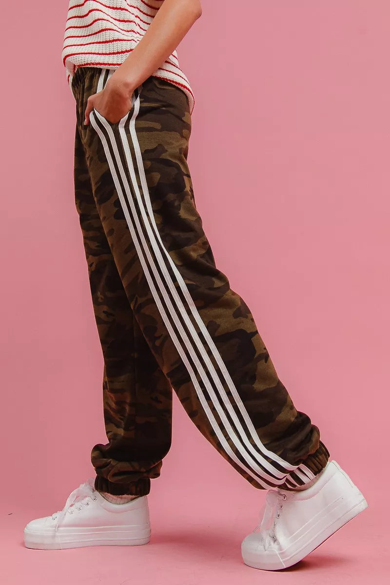 Camouflage track pants with bold white vertical side stripe and cuffed ankles.