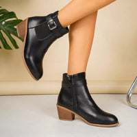 Point-toe block heel boots in black with buckle strap and visible side zipper