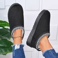 Black platform ankle boots with patterned trim and gold chain ankle bracelet