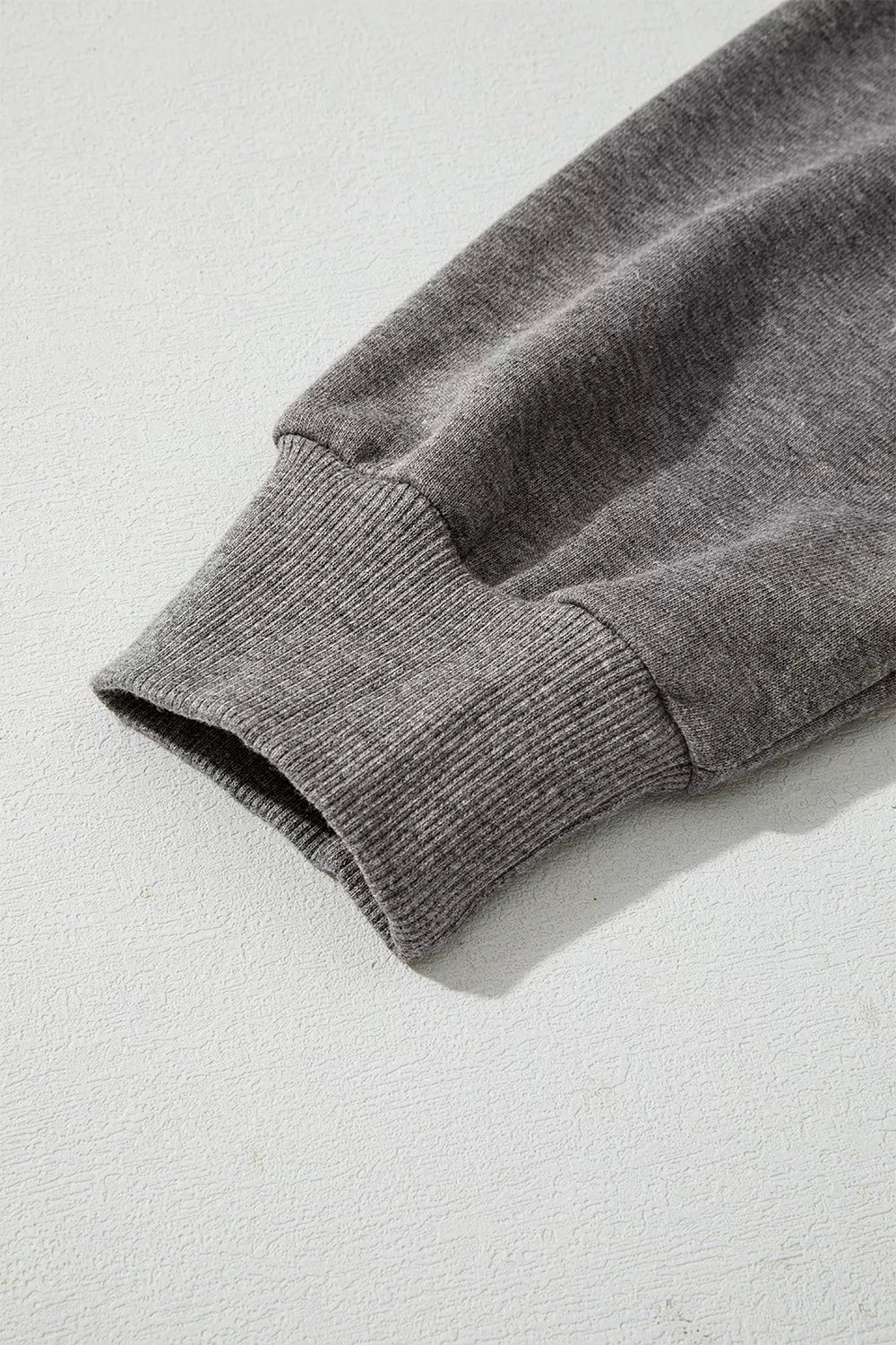 Dark gray hoodie sleeve close-up with ribbed cuff and textured knit finish