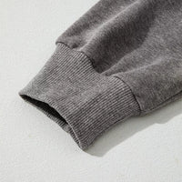 Dark gray hoodie sleeve close-up with ribbed cuff and textured knit finish