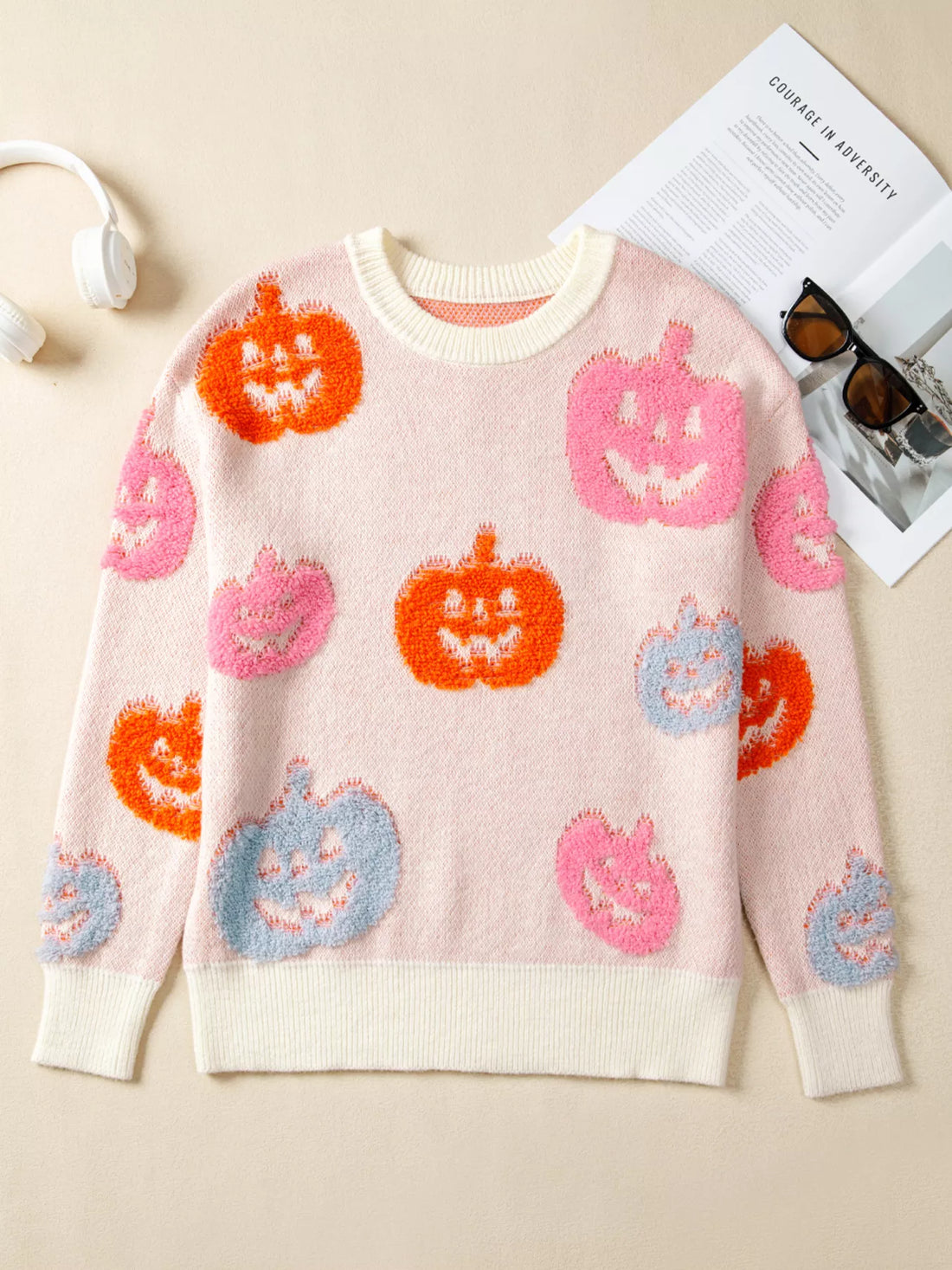 Dusty pink Halloween sweater with multicolor pumpkin faces and cream ribbed trim
