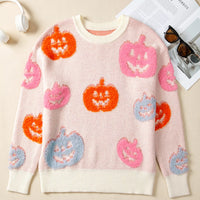 Dusty pink Halloween sweater with multicolor pumpkin faces and cream ribbed trim