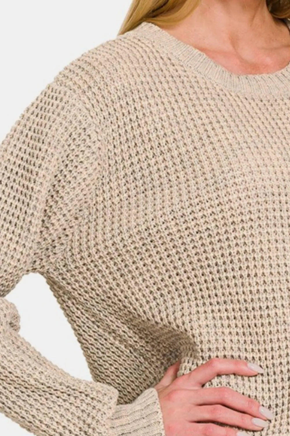 Beige waffle knit sweater close-up with ribbed cuff and textured fabric