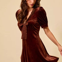 Burgundy velvet mini dress with lace V-neck, bow detail, and short sleeves.