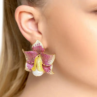 Gold-tone daffodil earrings with pink CZ floral top and faux pearl drop, shown on ear