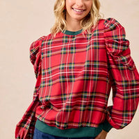 Red plaid puff-sleeve top with exaggerated shoulders and green ribbed cuffs at wrists