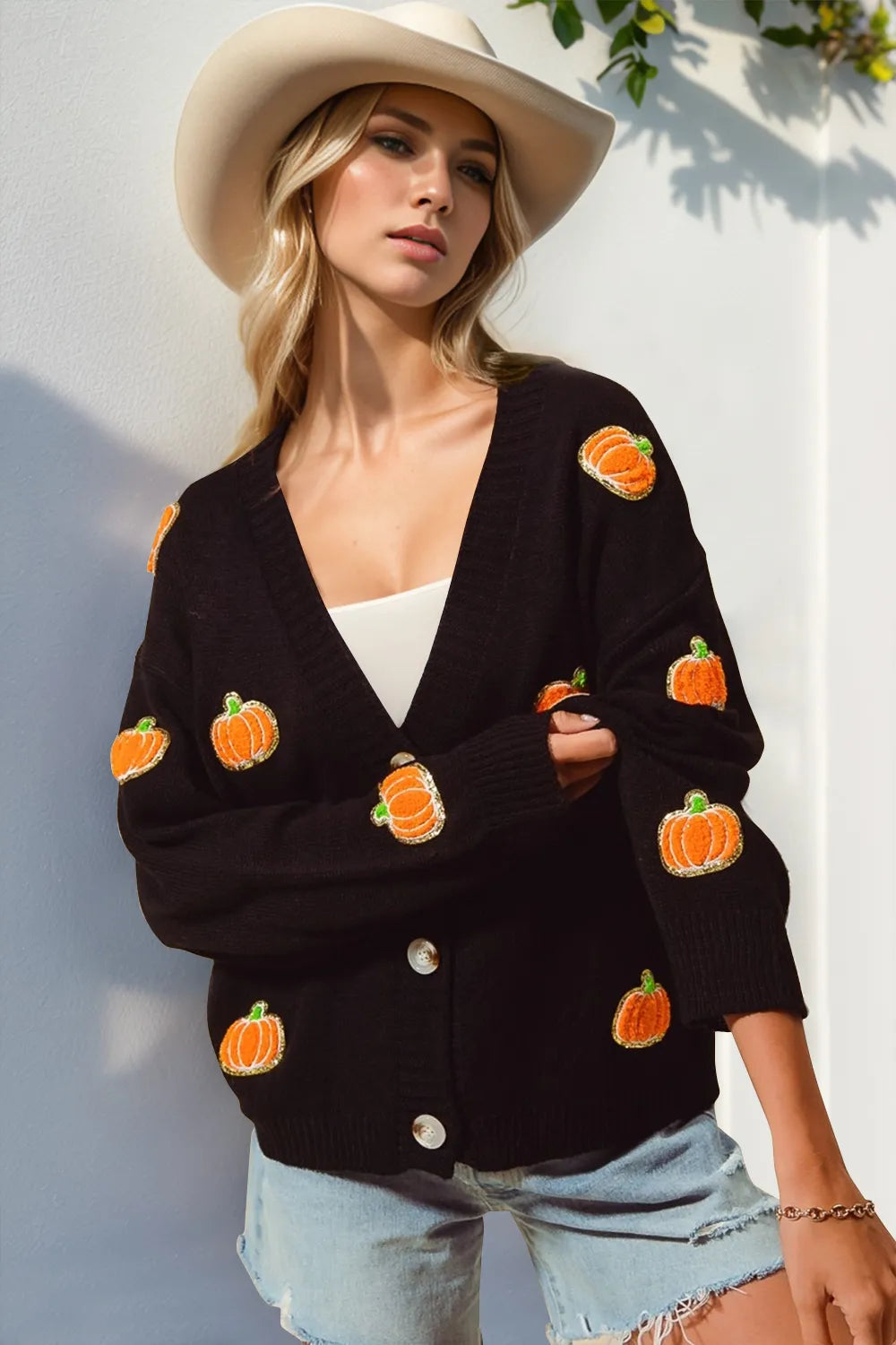 Black V-neck cardigan with long sleeves, orange pumpkin patches, and button front