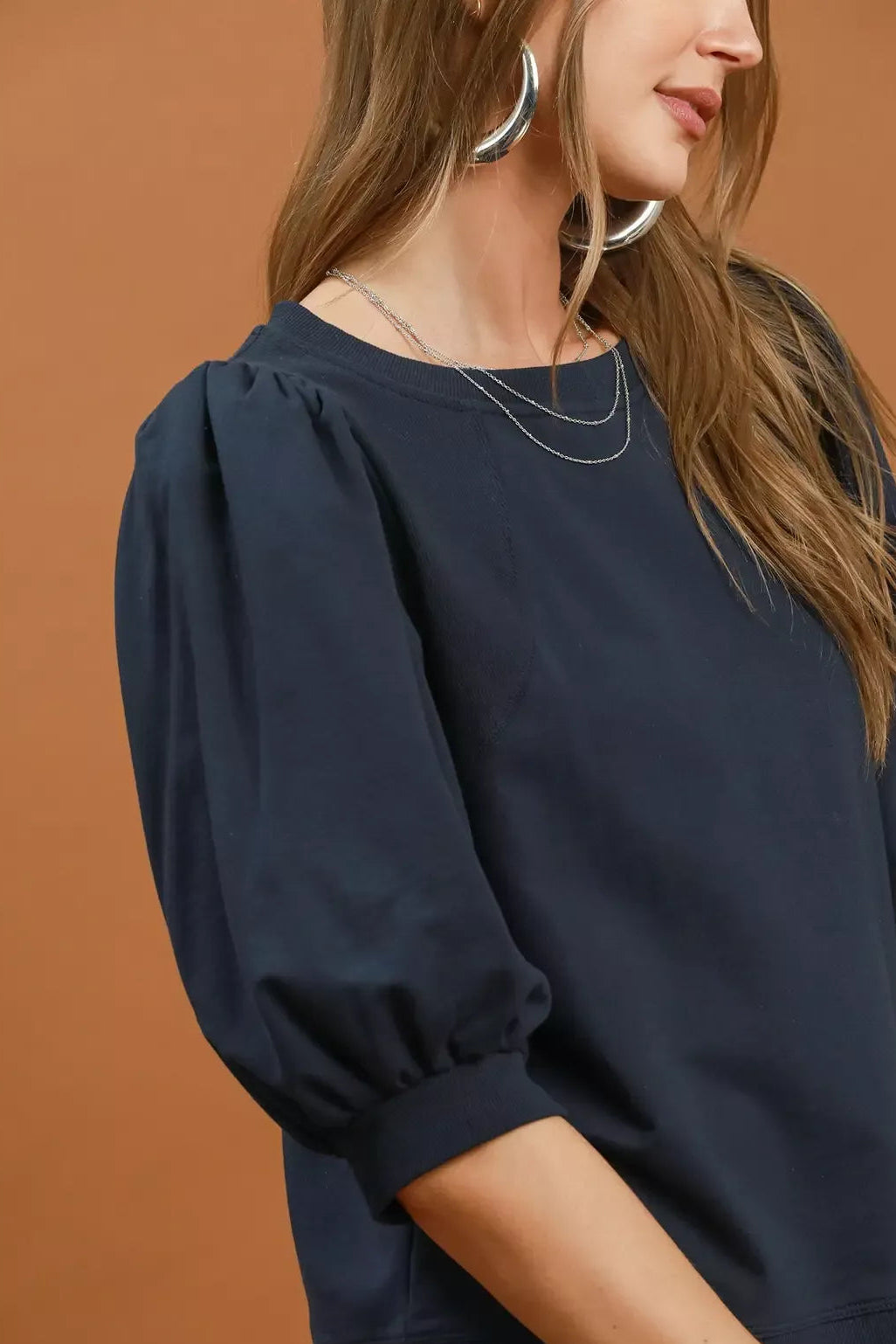 Close-up of navy round-neck sweatshirt with gathered puff sleeve detail