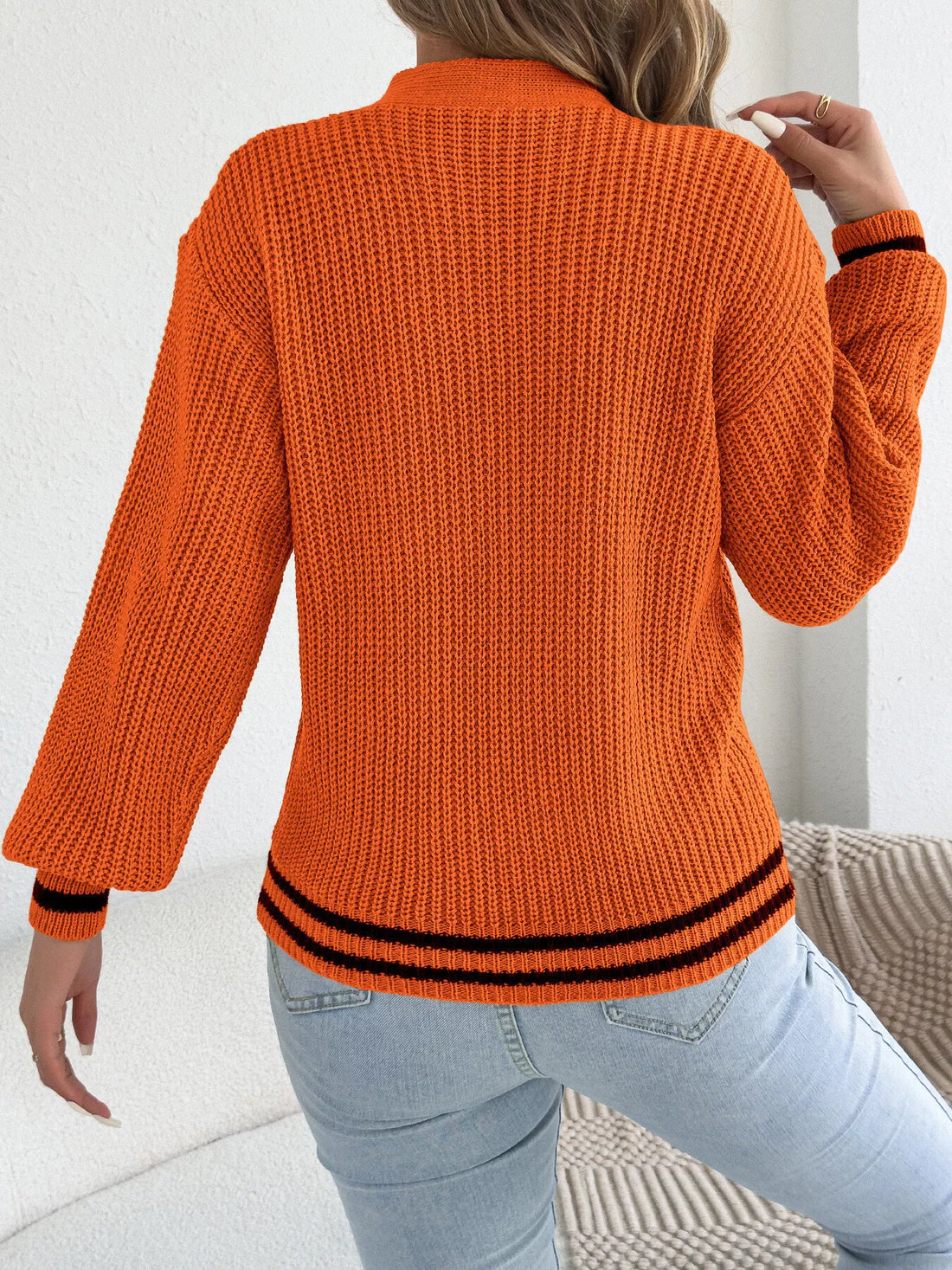 Orange cutout cable knit sweater, back view with ribbed hem and cuffs in black trim
