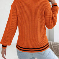 Orange cutout cable knit sweater, back view with ribbed hem and cuffs in black trim