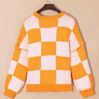 Orange and white checkered long-sleeve sweater with ribbed round neckline