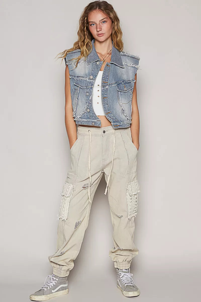 Light wash denim sleeveless vest with asymmetrical button front and raw hem