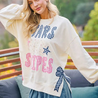 Cream sweatshirt with blue star and red/blue stripe patch prints plus bow