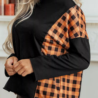 Black long-sleeve top with orange plaid sleeve panels and pumpkin face detail