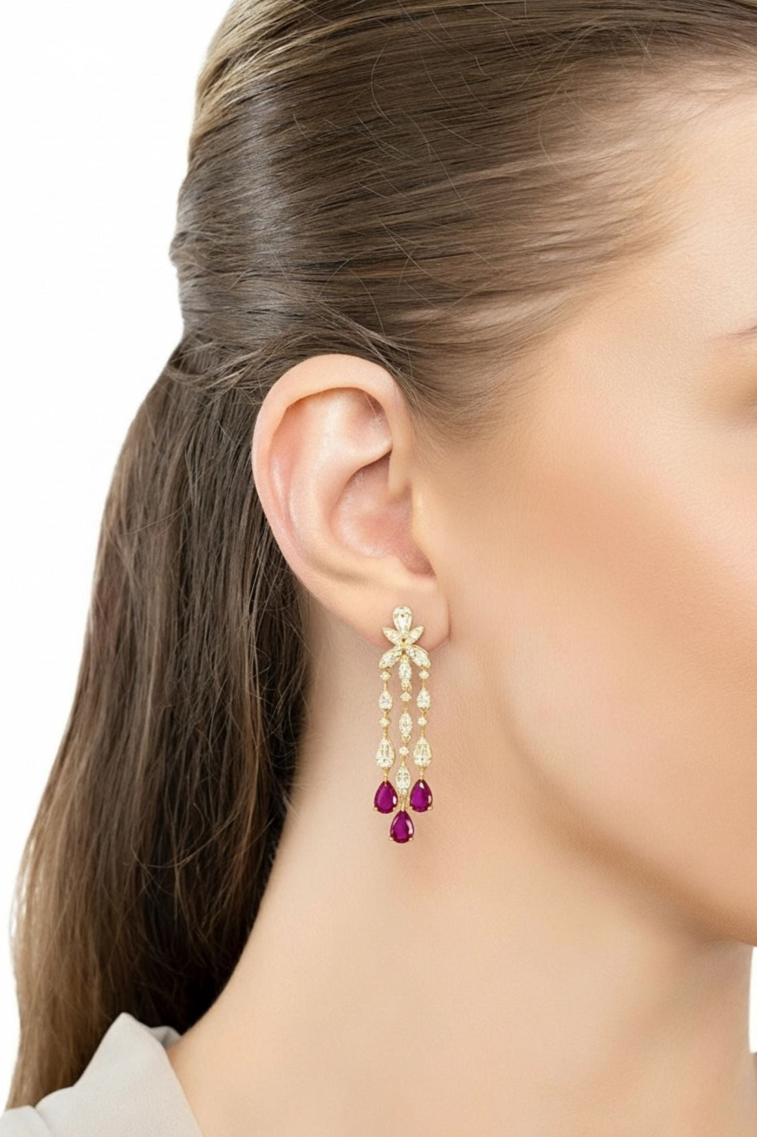 Gold chandelier drop earrings with purple teardrop stones, shown from side on ear