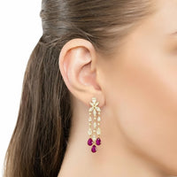 Gold chandelier drop earrings with purple teardrop stones, shown from side on ear