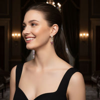 Gold drop earrings with crystal floral top and purple teardrop dangle on model