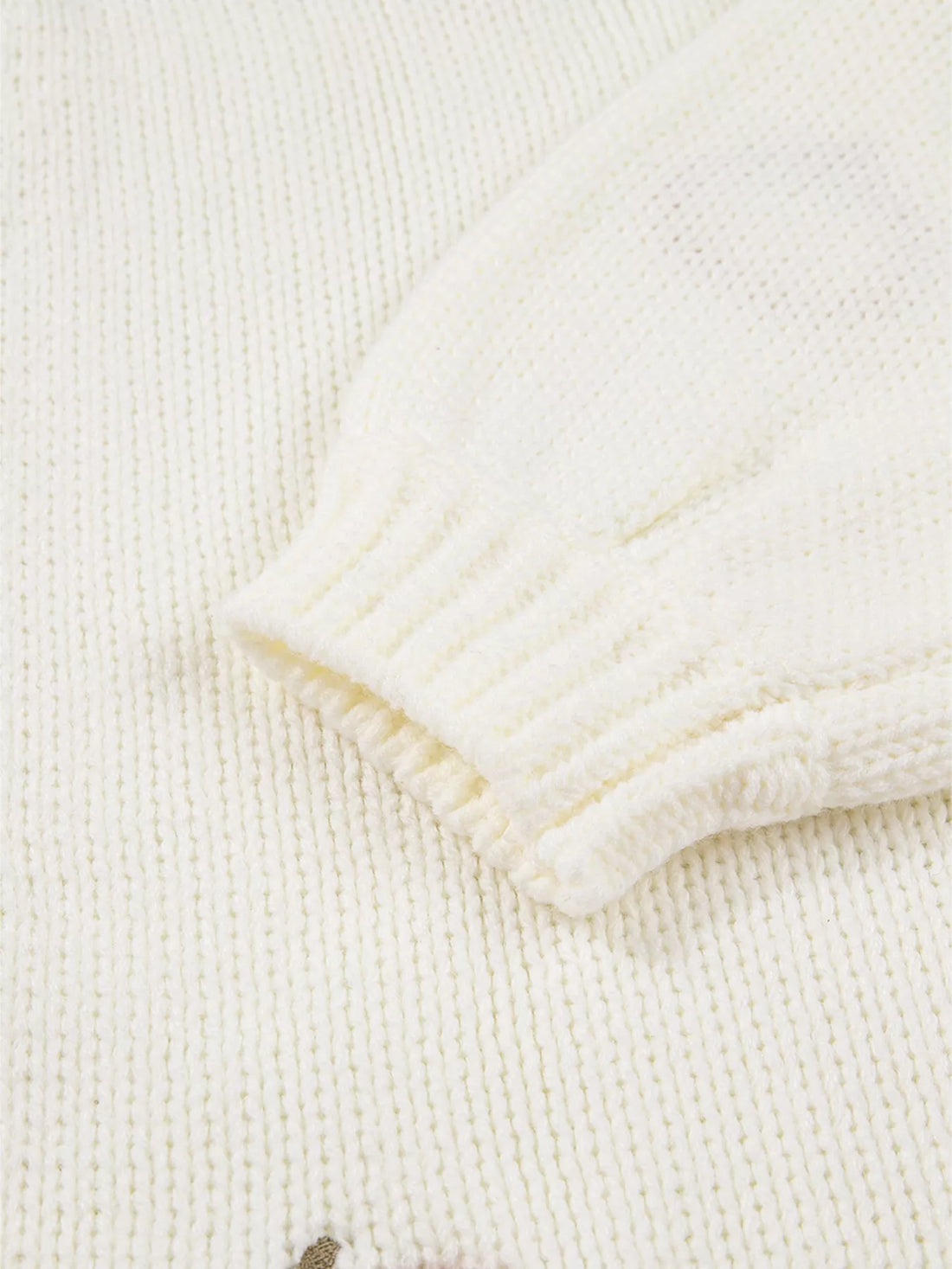 Close-up of off-white knit cardigan sleeve cuff with ribbed knit trim.