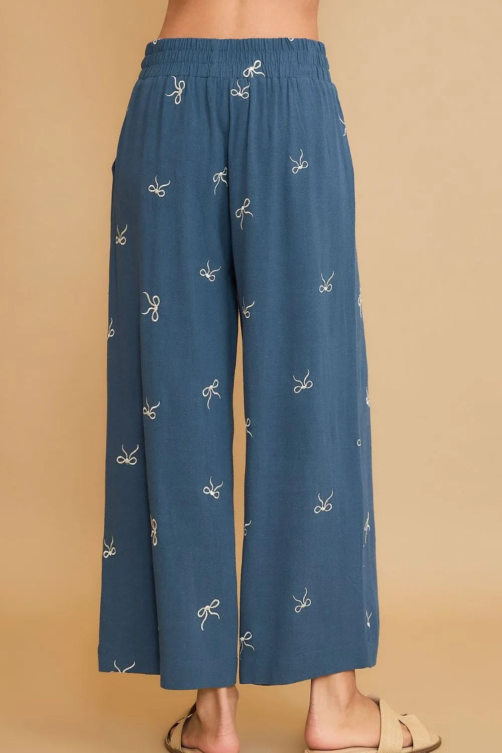 Dusty blue wide-leg drawstring pants with scattered bow embroidery, full view