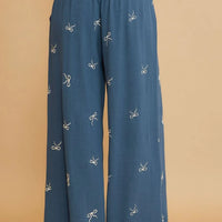 Dusty blue wide-leg drawstring pants with scattered bow embroidery, full view