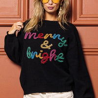 Black crewneck sweater with multicolor tinsel "Merry & bright" lettering, long sleeves.