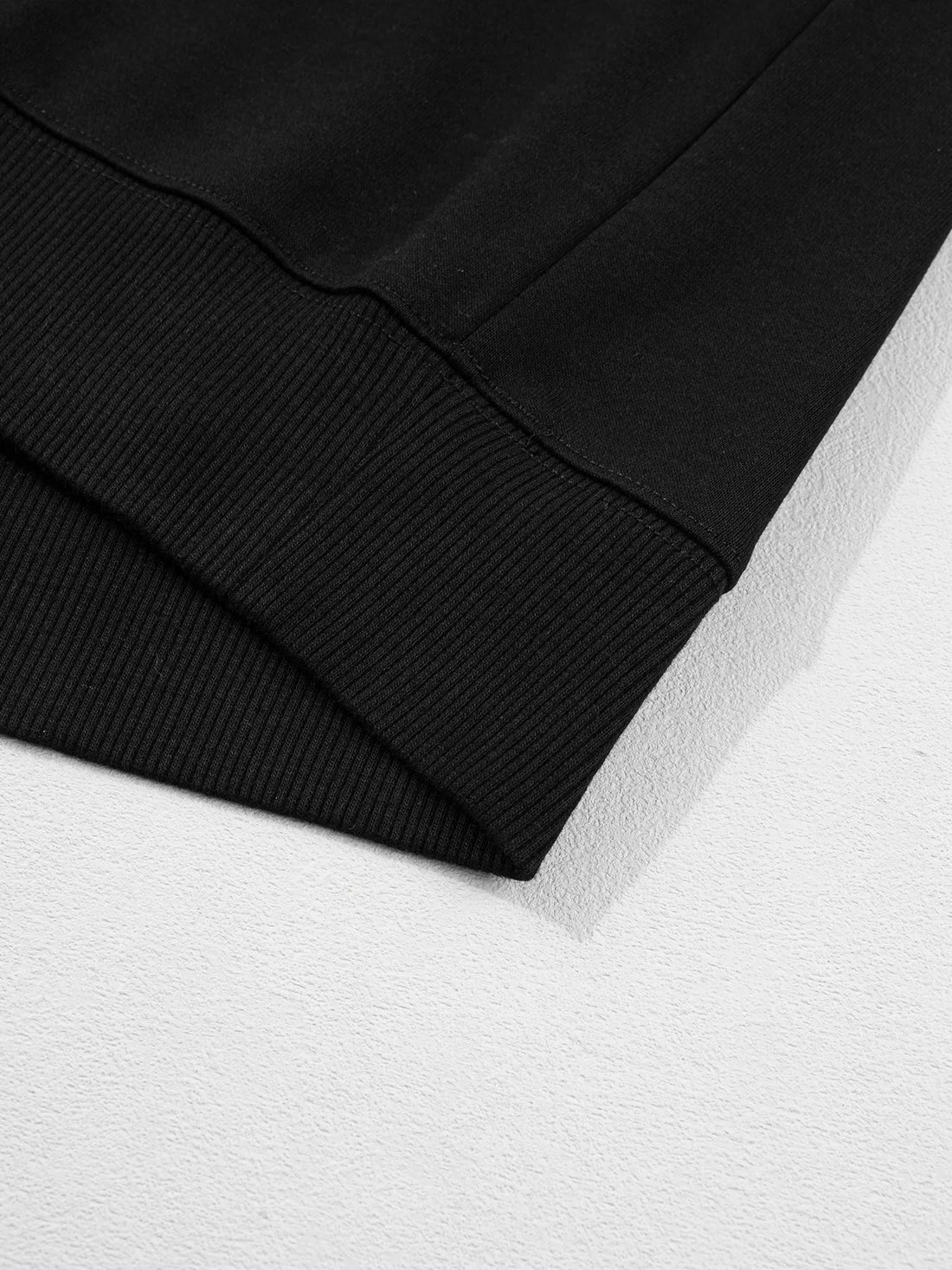 Black sweatshirt hem and ribbed sleeve cuff close-up