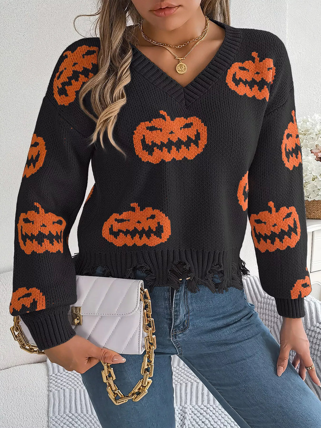 Black V-neck pumpkin sweater, long sleeves, orange jack-o’-lantern intarsia and frayed hem