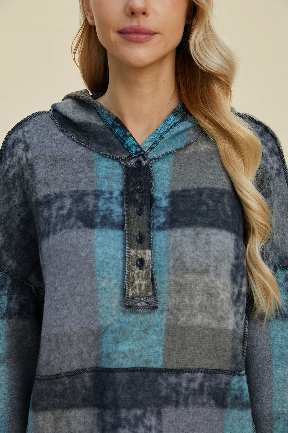 Plaid fleece hoodie close-up: hooded neckline with half-zip placket and textured pocket.