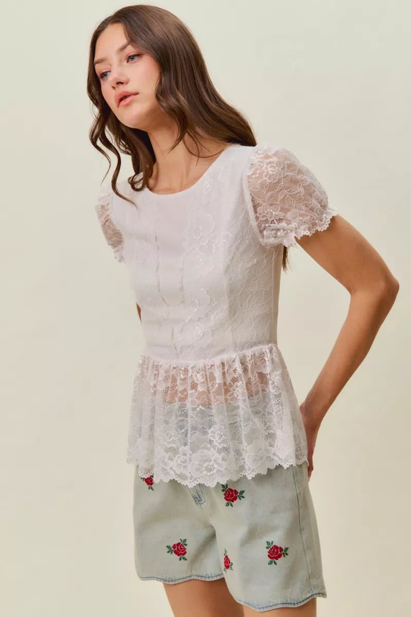Model wearing light-wash denim shorts with rose embroidery and scallop hem