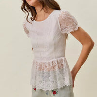 Model wearing light-wash denim shorts with rose embroidery and scallop hem