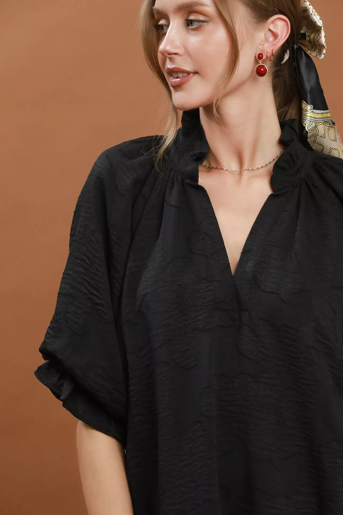 Black V-neck textured dress detail view with gathered neckline and flutter sleeves