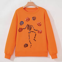 Orange Halloween crewneck sweatshirt with sequin skeleton and critter icons, on hanger