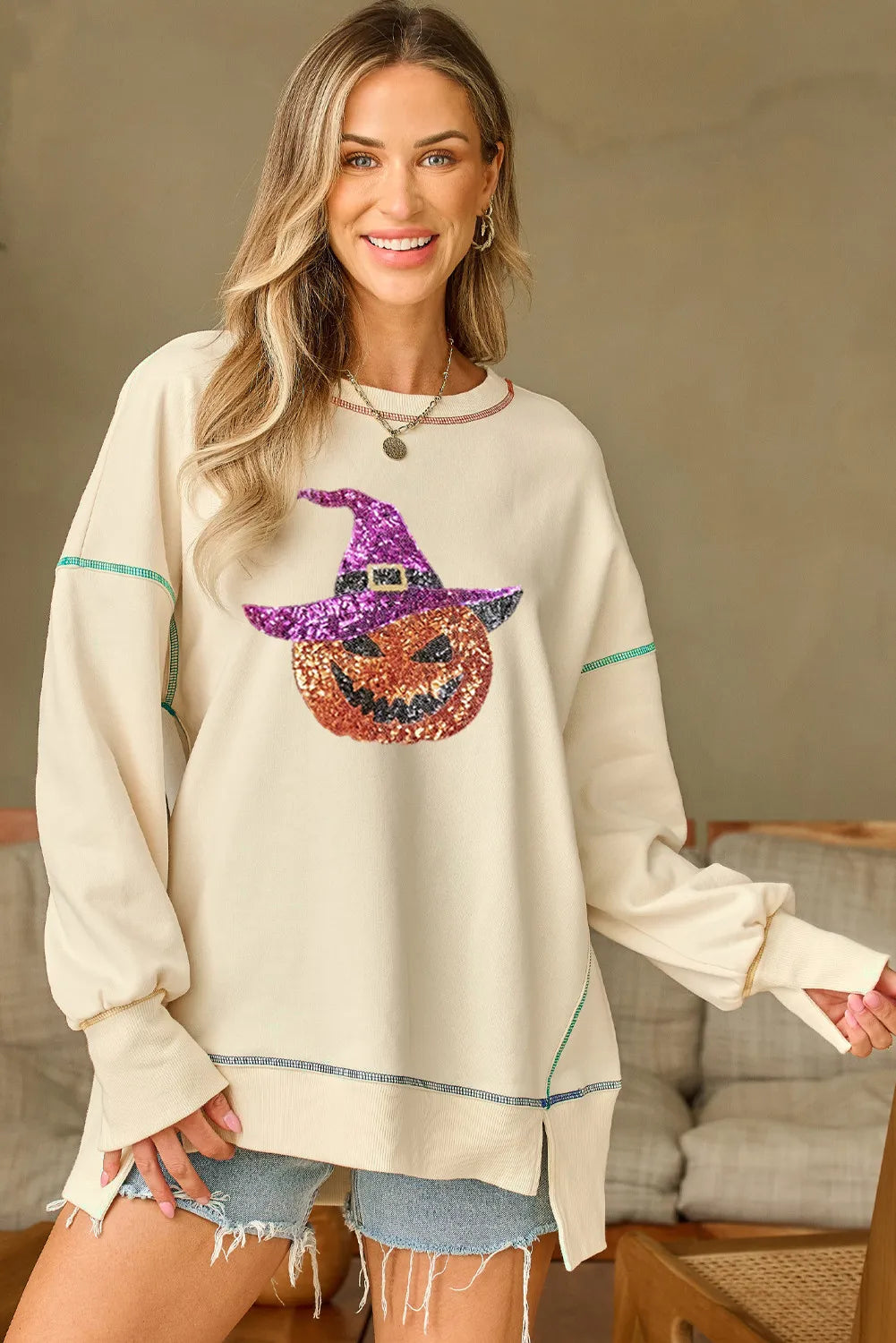 Ivory long-sleeve sweatshirt with sequin pumpkin graphic and contrast trim at cuffs