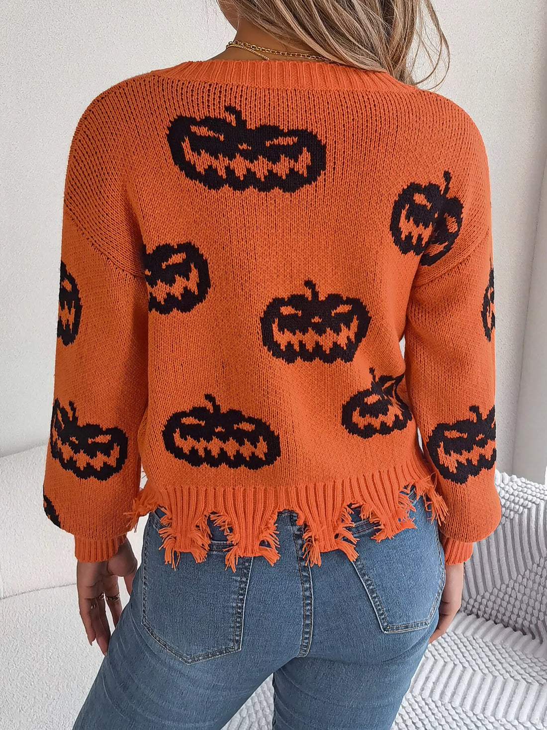 Back view orange pumpkin print sweater with fringed hem and long sleeves