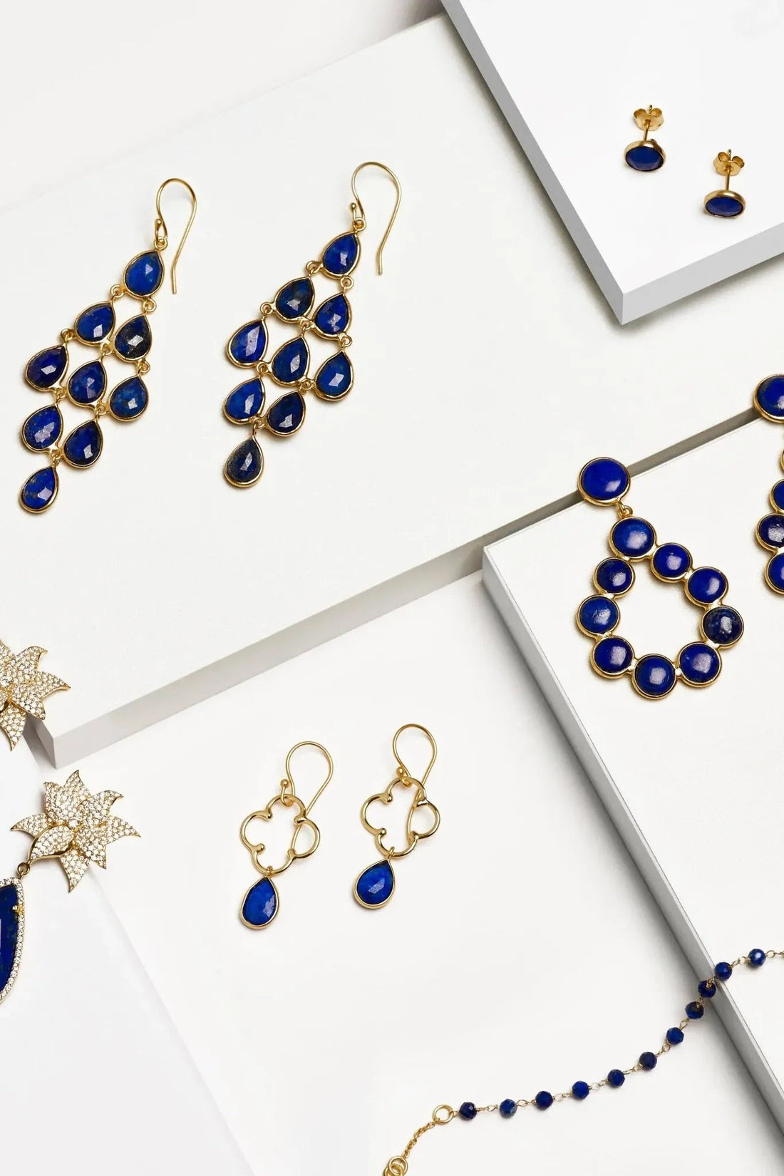 Gold-tone lapis blue teardrop cascade earrings on white jewelry display