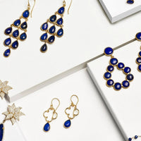 Gold-tone lapis blue teardrop cascade earrings on white jewelry display