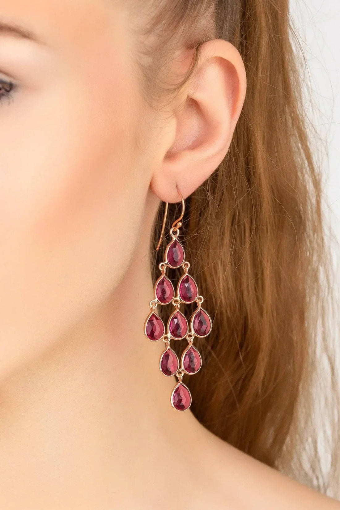 Rose gold cascade earrings with pink teardrop gems hanging below the ear