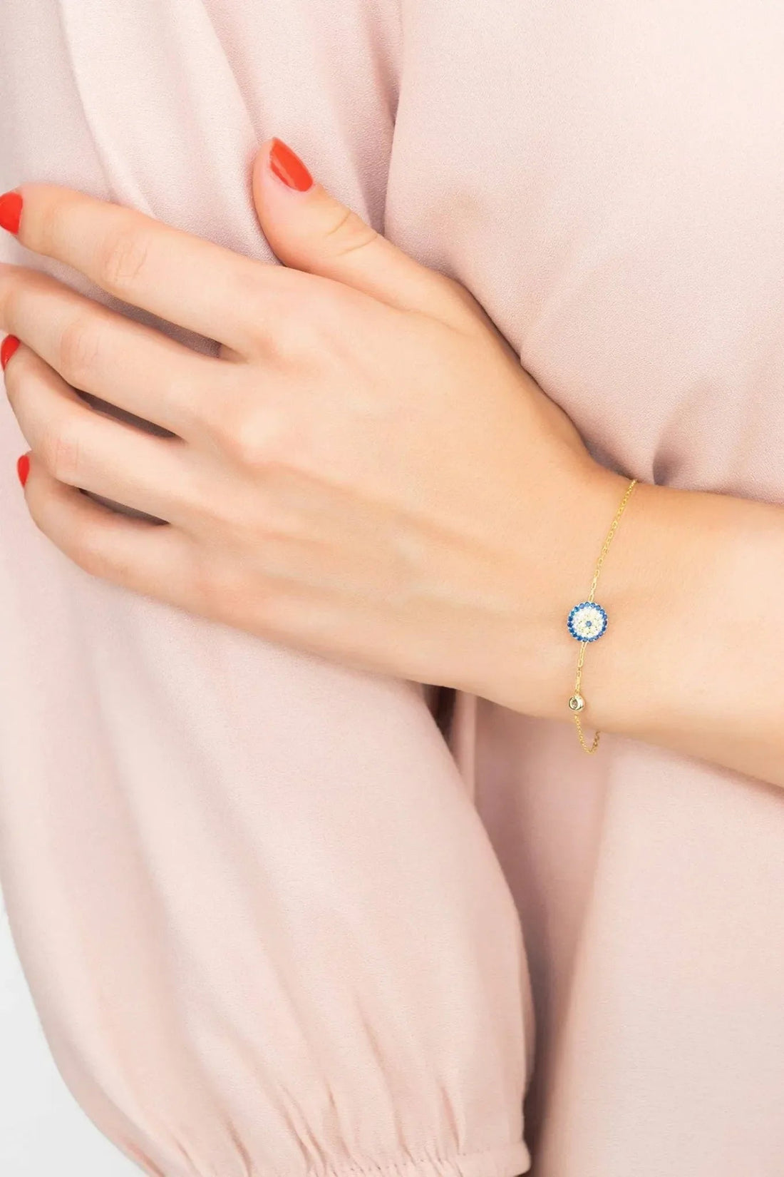 Gold evil eye bracelet with blue round charm on wrist